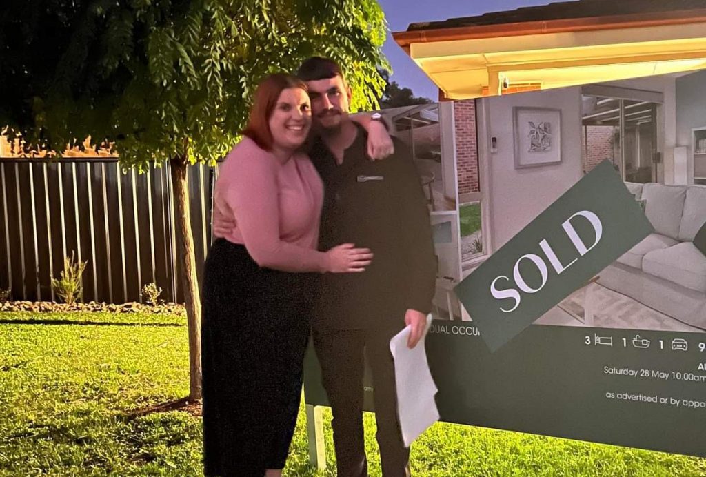 Portfolio Manager Ashlyn Maloney and her partner next to their first home!